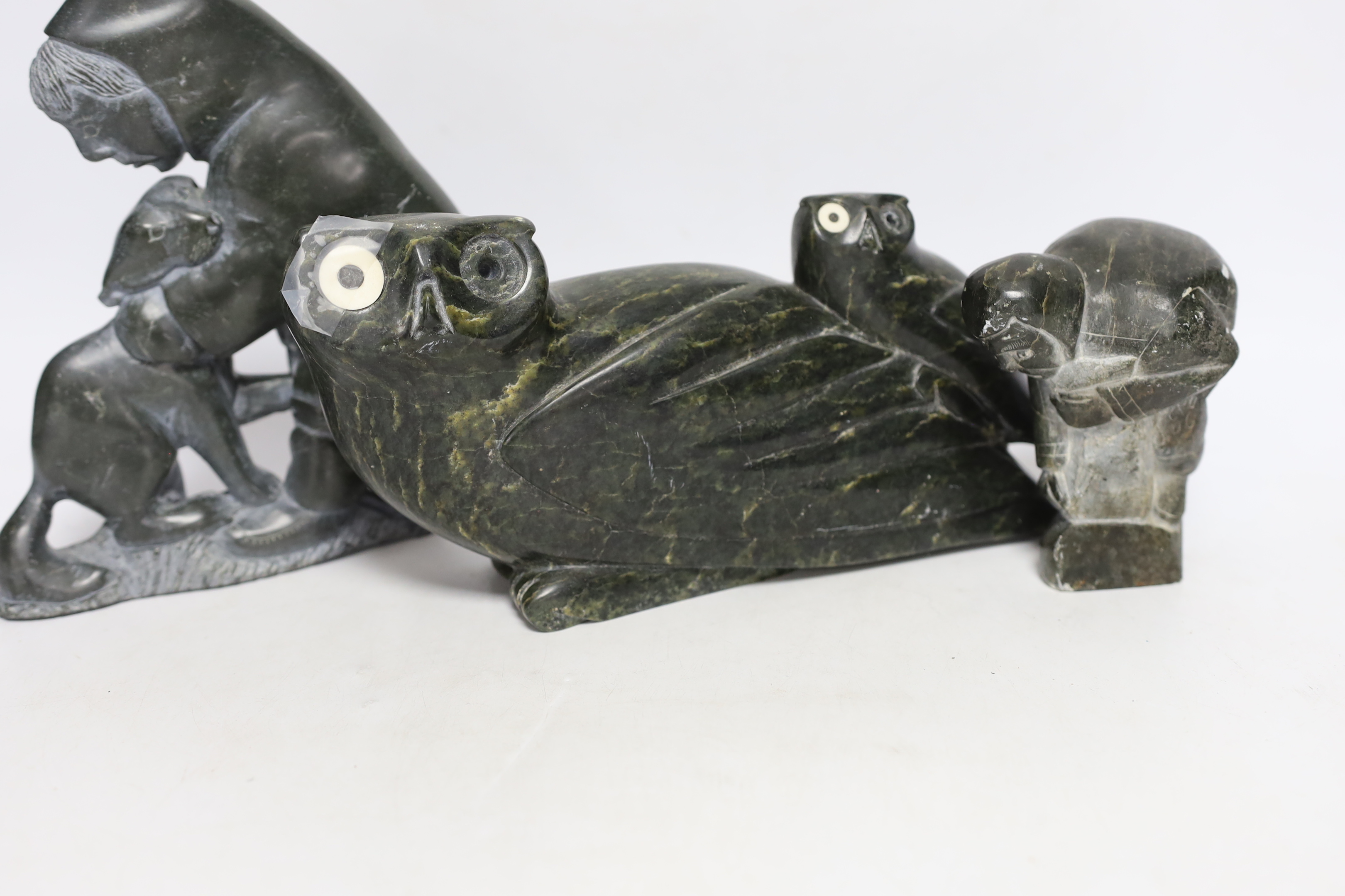 Three 20th century Inuit stone figural carvings, one bearing marine bone eyes, largest 19cm high